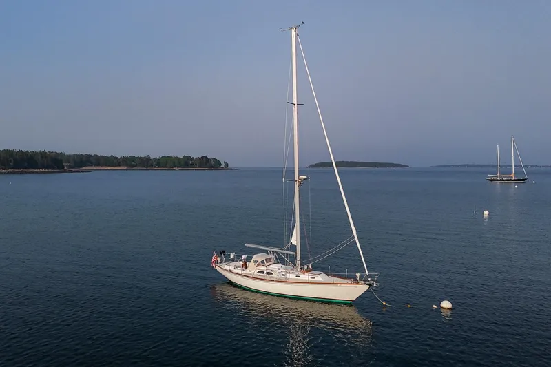 Loon Yacht Photos Pics Sailboat Hinckley Sou'wester 42, 1988 model, anchored in calm waters with distant islands.