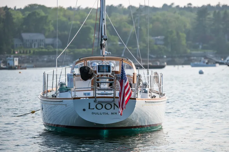 Loon Yacht Photos Pics 1988 Hinckley Sou'wester 42 sailboat on calm water, displaying an American flag.