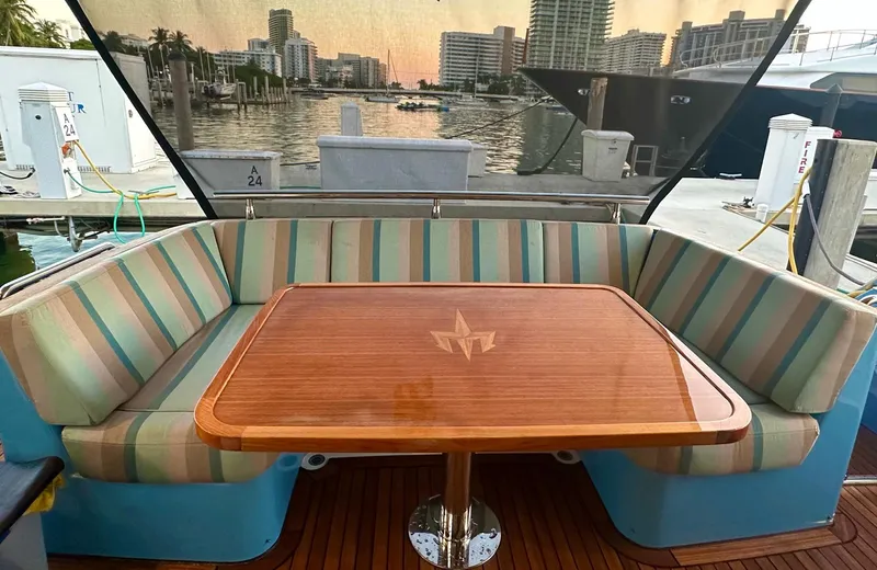Oasis Yacht Photos Pics Luxurious 2021 Outer Reef Trident 620 yacht with elegant striped seating and polished wooden table.