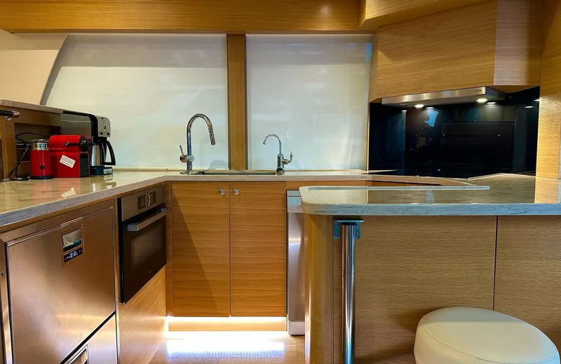 Oasis Yacht Photos Pics Modern kitchen interior of 2021 Outer Reef Trident 620 yacht with wood cabinetry and stainless appliances.