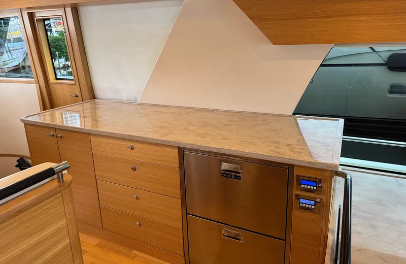 Oasis Yacht Photos Pics Modern kitchen interior of 2021 Outer Reef Trident 620 yacht with wooden cabinetry and stainless steel appliances.