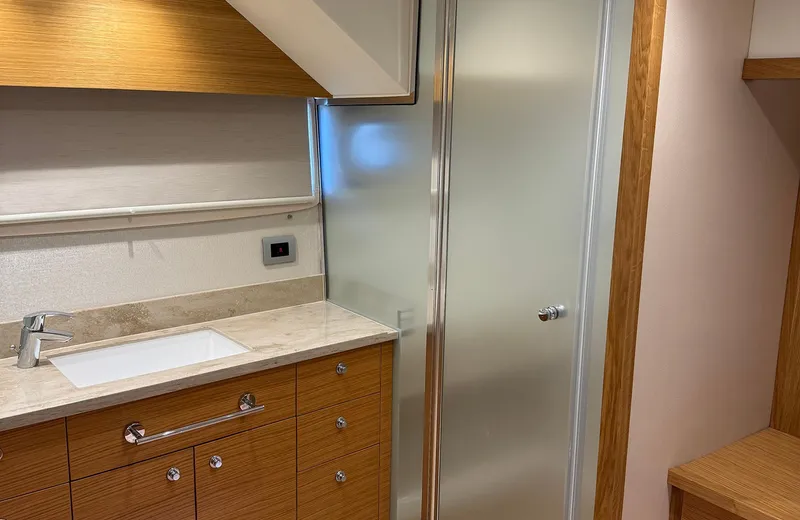 Oasis Yacht Photos Pics Modern bathroom interior on 2021 Outer Reef Trident 620 yacht, featuring wood cabinetry and frosted glass door.