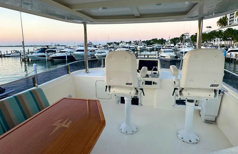 Oasis Yacht Photos Pics Luxury Outer Reef Trident 620 yacht deck with helm chairs, overlooking marina at sunset.
