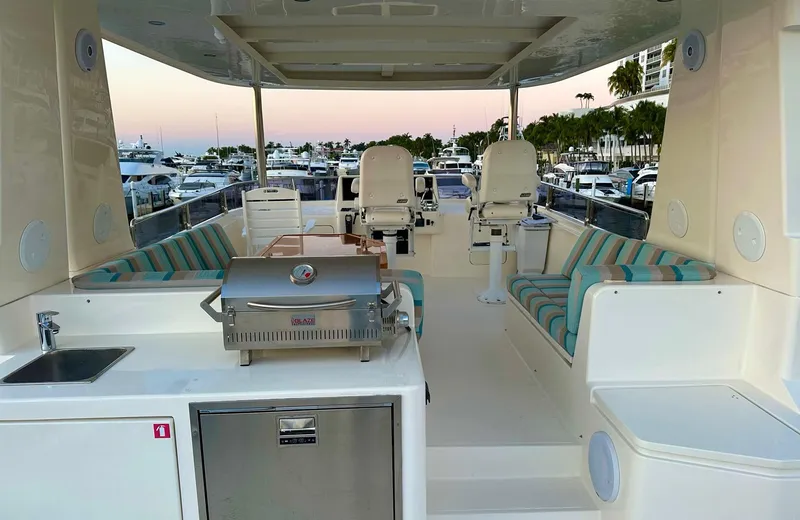 Oasis Yacht Photos Pics Luxurious 2021 Outer Reef Trident 620 yacht deck with seating, grill, and marina view.
