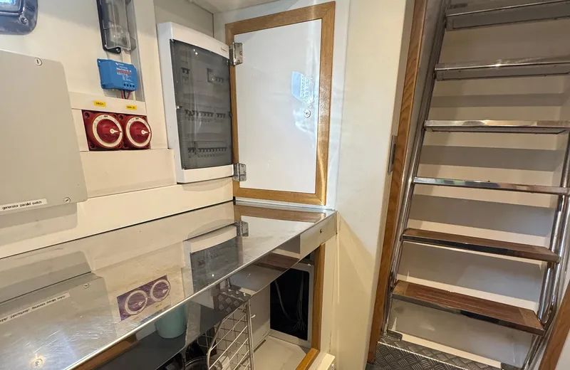 Oasis Yacht Photos Pics Engine room of 2021 Outer Reef Trident 620 yacht with control panels and ladder.