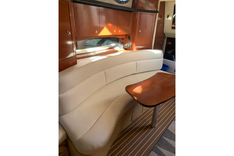 Maximus Yacht Photos Pics Interior of 2005 Sea Ray 340 Sundancer with curved seating and wooden table.