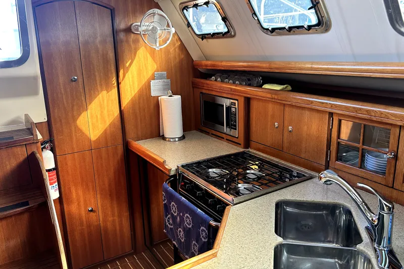 Island Myst II Yacht Photos Pics 2007 Hunter 41 Deck Salon kitchen with wood cabinetry, stove, microwave, and sink.