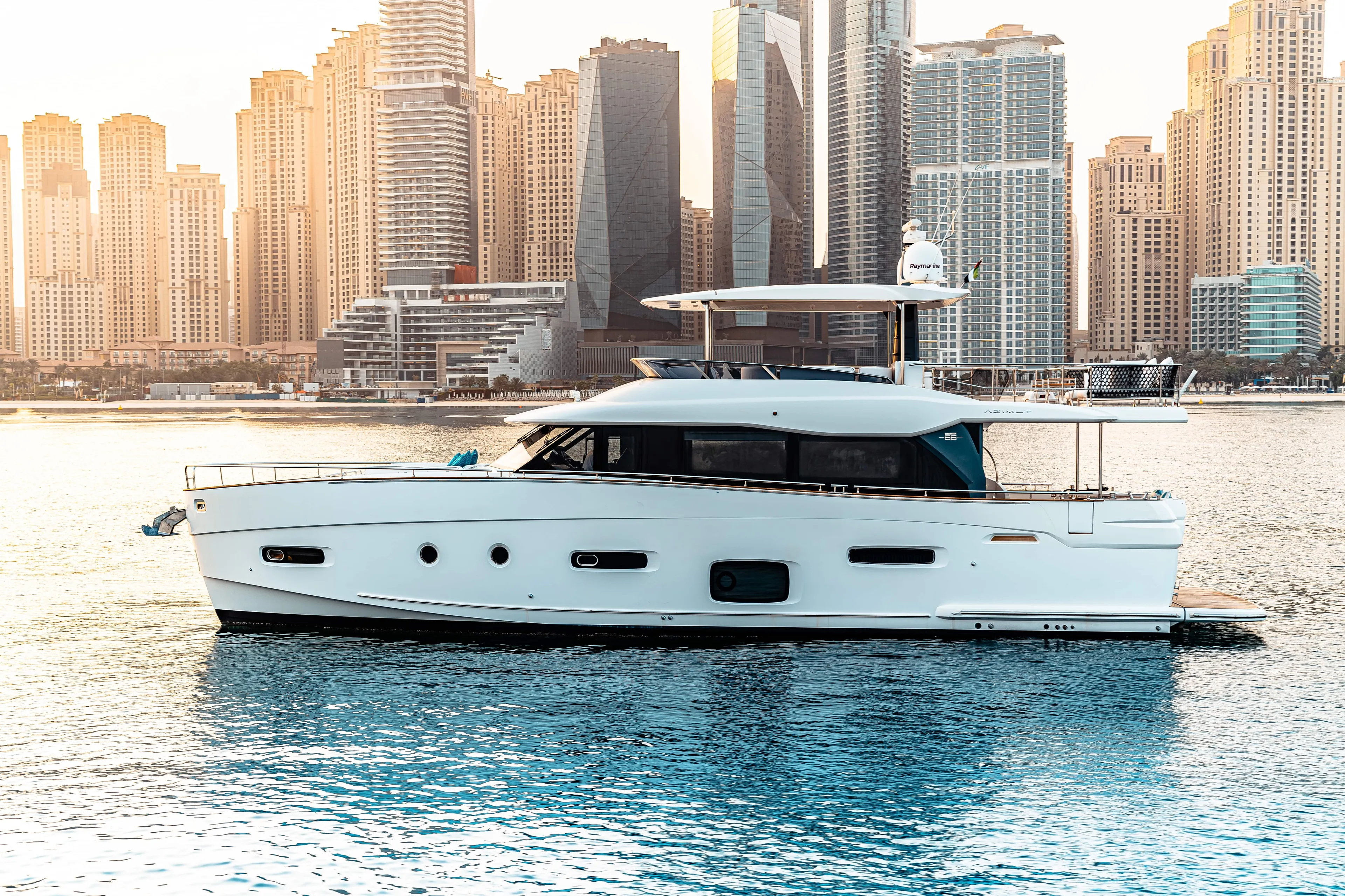Fat Boy Yacht Photos Pics Azimut Magellano 66 yacht, 2020 model, cruising near modern city skyline at sunset.