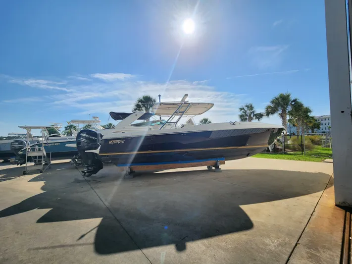  Yacht Photos Pics 2008 Intrepid 323 Cuddy boat on display under bright sun, with palm trees in background.