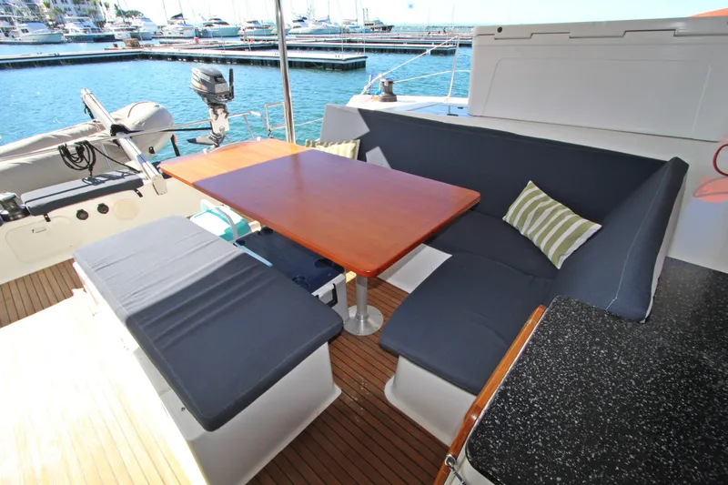 Yacht Photos Pics Outdoor seating area on 2013 Fountaine Pajot Helia 44 catamaran, featuring a wooden table and cushions.