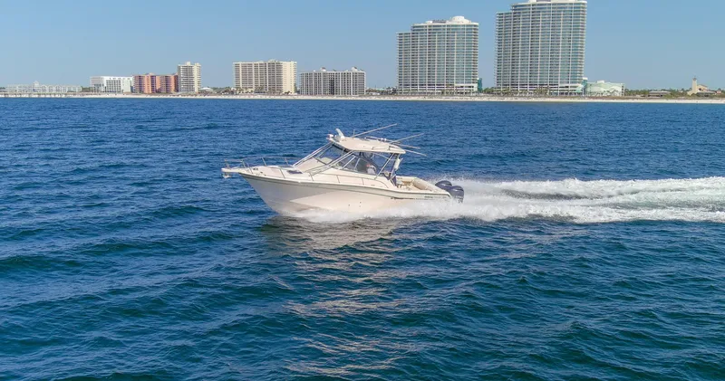  Yacht Photos Pics 2009 Grady-White 330 Express boat cruising on ocean near city skyline.
