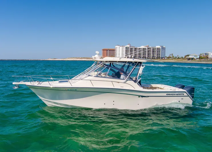  Yacht Photos Pics 2009 Grady-White 330 Express boat cruising on clear blue water near coastal buildings.