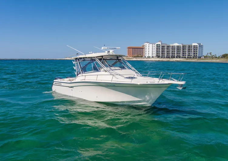  Yacht Photos Pics 2009 Grady-White 330 Express boat on clear blue water near coastal buildings.