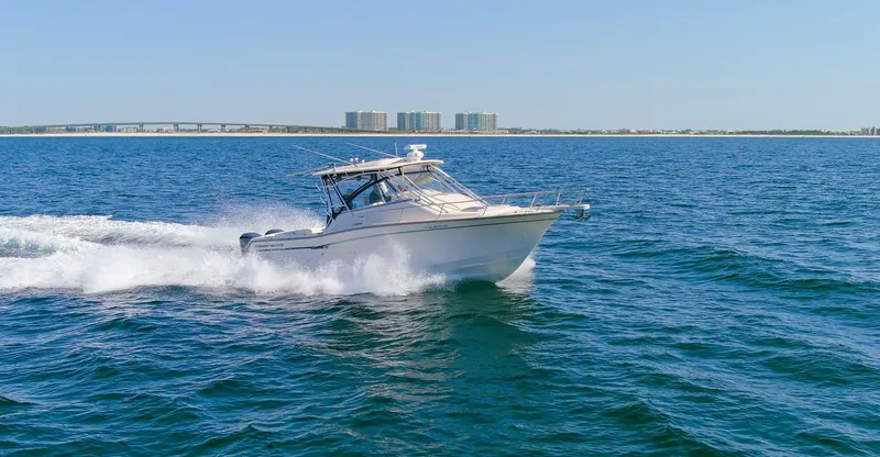  Yacht Photos Pics 2009 Grady-White 330 Express boat cruising on open water, cityscape in background.