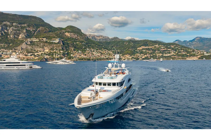 Latitude Yacht Photos Pics Luxurious 2009 Timmerman Expedition Tri-Deck yacht cruising near scenic coastal mountains.