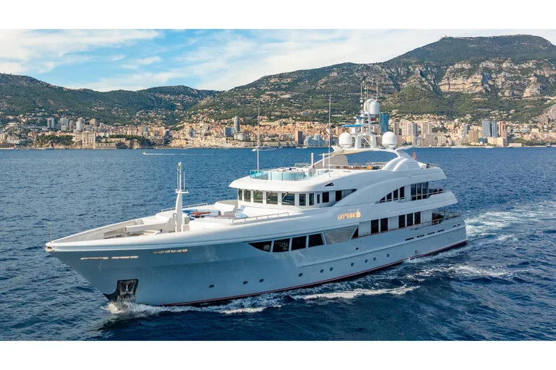 Latitude Yacht Photos Pics Luxurious 2009 Timmerman Expedition Tri-Deck yacht cruising near scenic coastal city.