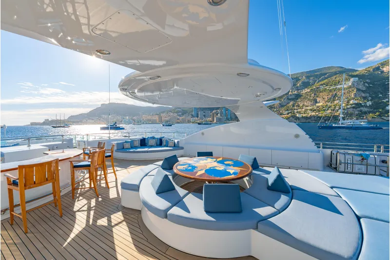 Latitude Yacht Photos Pics Luxurious Timmerman Expedition Tri-Deck yacht deck with seating, ocean view, and coastal backdrop.