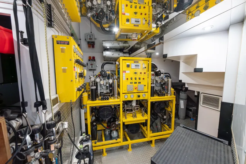 Latitude Yacht Photos Pics Engine room of 2009 Timmerman Expedition Tri-Deck yacht with yellow machinery and control panels.