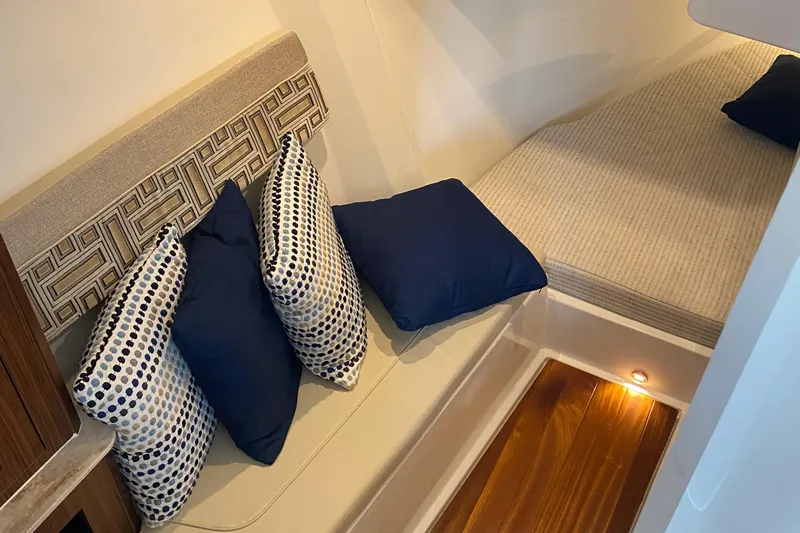  Yacht Photos Pics 2022 Pursuit DC 365 cabin interior with seating, cushions, and wooden flooring.