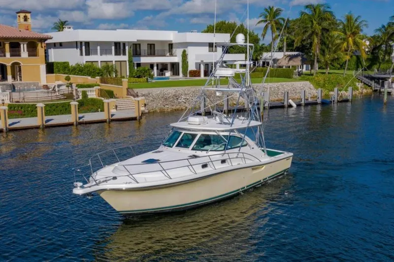Brown Eyed Girl Yacht Photos Pics 2004 Pursuit 3800 Express yacht cruising near waterfront homes, surrounded by palm trees.