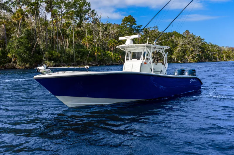  Yacht Photos Pics 2014 Yellowfin 32 Offshore boat on a scenic waterway with lush greenery.