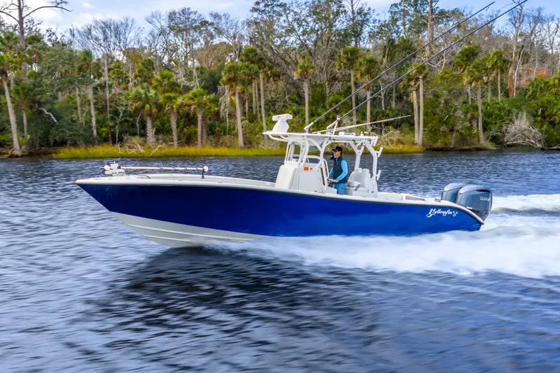  Yacht Photos Pics 2014 Yellowfin 32 Offshore boat cruising on a scenic river with lush forest backdrop.