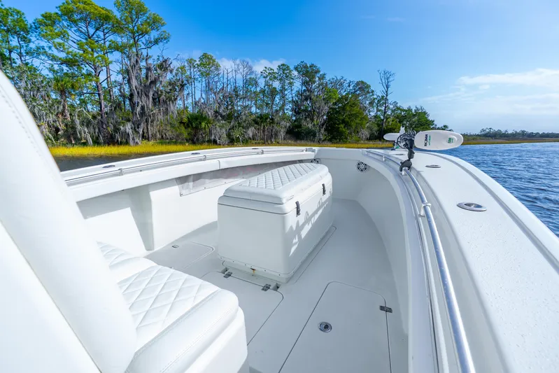  Yacht Photos Pics 2014 Yellowfin 32 Offshore boat interior with white seating, near lush shoreline.