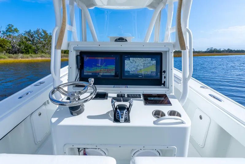  Yacht Photos Pics 2014 Yellowfin 32 Offshore boat dashboard with navigation screens and steering wheel on open water.
