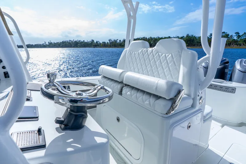  Yacht Photos Pics 2014 Yellowfin 32 Offshore boat interior with steering wheel and cushioned seating, on a sunny day.