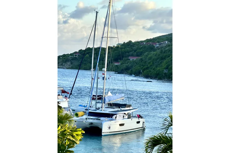 Knotty Cat Yacht Photos Pics 2022 Fountaine Pajot Tanna 47 catamaran anchored in scenic coastal waters.