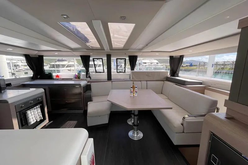 Knotty Cat Yacht Photos Pics Luxurious interior of 2022 Fountaine Pajot Tanna 47 catamaran with modern seating and kitchen.