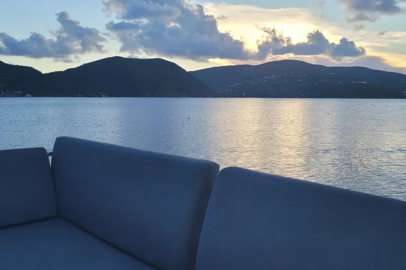 Knotty Cat Yacht Photos Pics Sunset view from Fountaine Pajot Tanna 47 yacht, 2022, overlooking serene waters and hills.