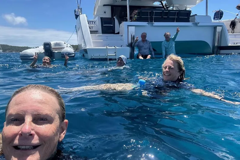 Knotty Cat Yacht Photos Pics People swimming near a 2022 Fountaine Pajot Tanna 47 catamaran in clear blue water.