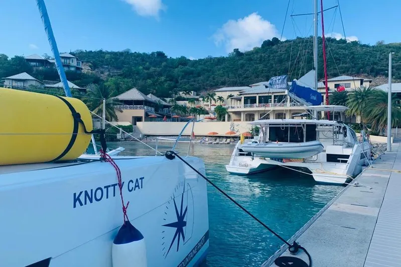 Knotty Cat Yacht Photos Pics 2022 Fountaine Pajot Tanna 47 catamaran docked in a scenic marina.