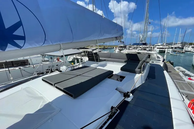 Knotty Cat Yacht Photos Pics 2022 Fountaine Pajot Tanna 47 catamaran with spacious deck and seating, docked in marina.