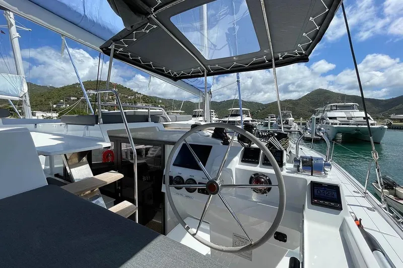 Knotty Cat Yacht Photos Pics 2022 Fountaine Pajot Tanna 47 yacht helm with scenic marina backdrop.