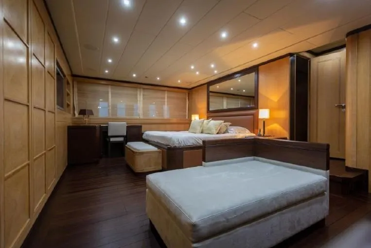  Yacht Photos Pics Luxurious bedroom interior on 2004 Mangusta 108 yacht, featuring elegant wood paneling and modern lighting.