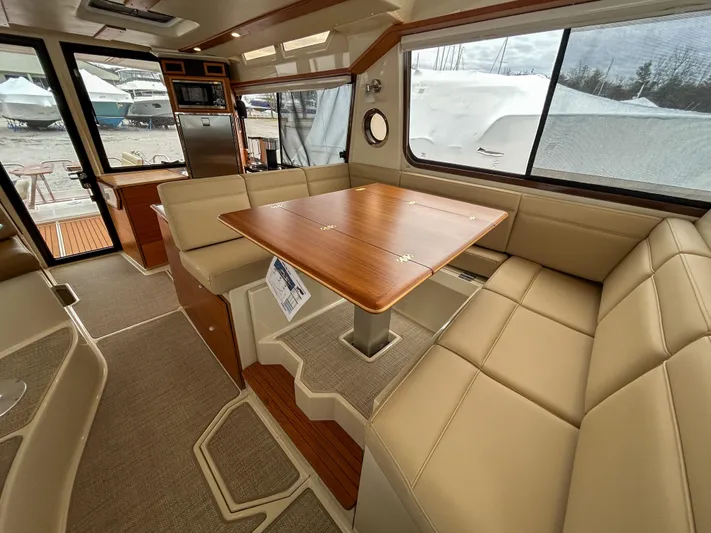  Yacht Photos Pics 2023 Ranger Tugs R-43 CB interior with beige seating and wooden table, showcasing modern design.