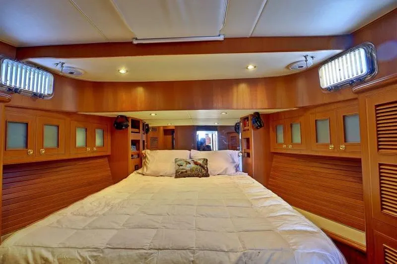 Sharki's Wake Yacht Photos Pics Luxurious bedroom interior of 2016 North Pacific 45 Pilothouse yacht with wood paneling.