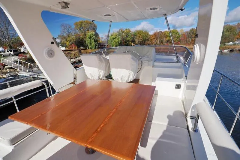 Sharki's Wake Yacht Photos Pics 2016 North Pacific 45 Pilothouse yacht deck with wooden table and seating.