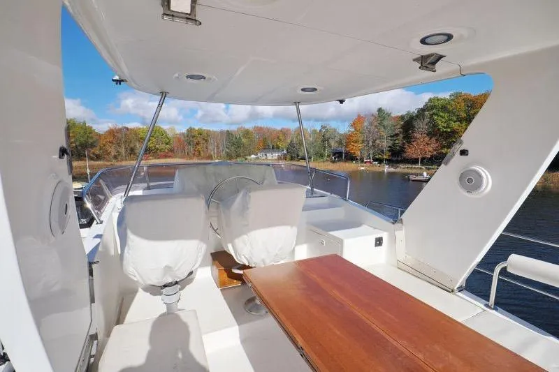 Sharki's Wake Yacht Photos Pics 2016 North Pacific 45 Pilothouse boat interior with covered seats and wooden table, scenic lake view.