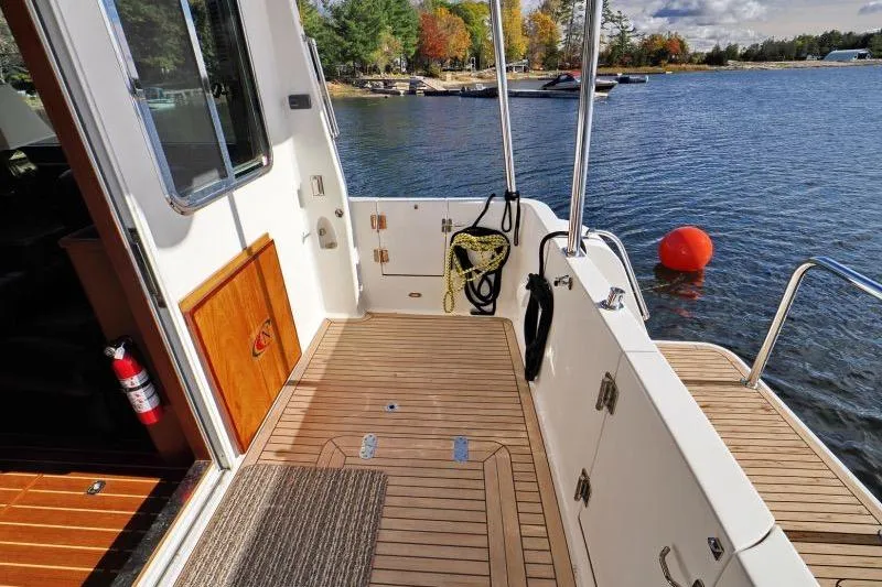 Sharki's Wake Yacht Photos Pics 2016 North Pacific 45 Pilothouse boat deck with wooden flooring, docked by a lake.