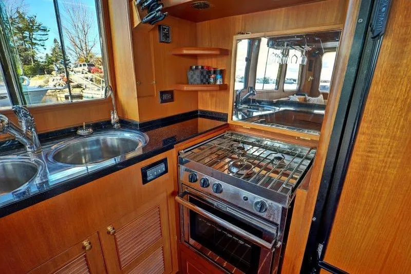 Sharki's Wake Yacht Photos Pics 2016 North Pacific 45 Pilothouse kitchen with stove, sink, and wooden cabinetry.