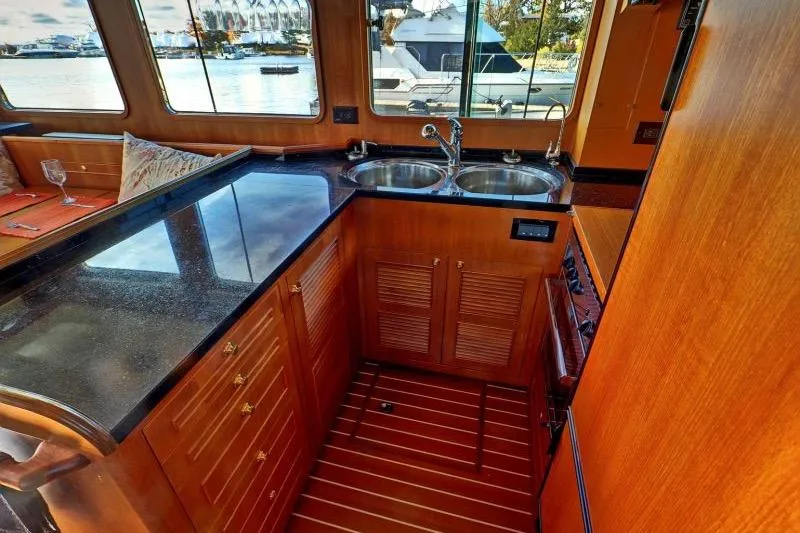 Sharki's Wake Yacht Photos Pics Luxurious 2016 North Pacific 45 Pilothouse yacht kitchen with dual sinks and wooden cabinetry.