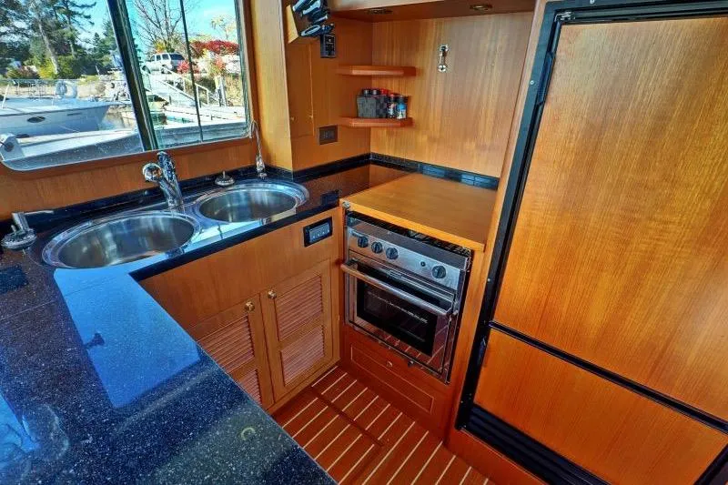 Sharki's Wake Yacht Photos Pics 2016 North Pacific 45 Pilothouse kitchen with wood cabinetry, dual sinks, and modern appliances.