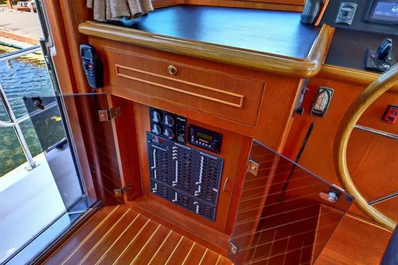 Sharki's Wake Yacht Photos Pics Interior of 2016 North Pacific 45 Pilothouse with control panel and wooden cabinetry.