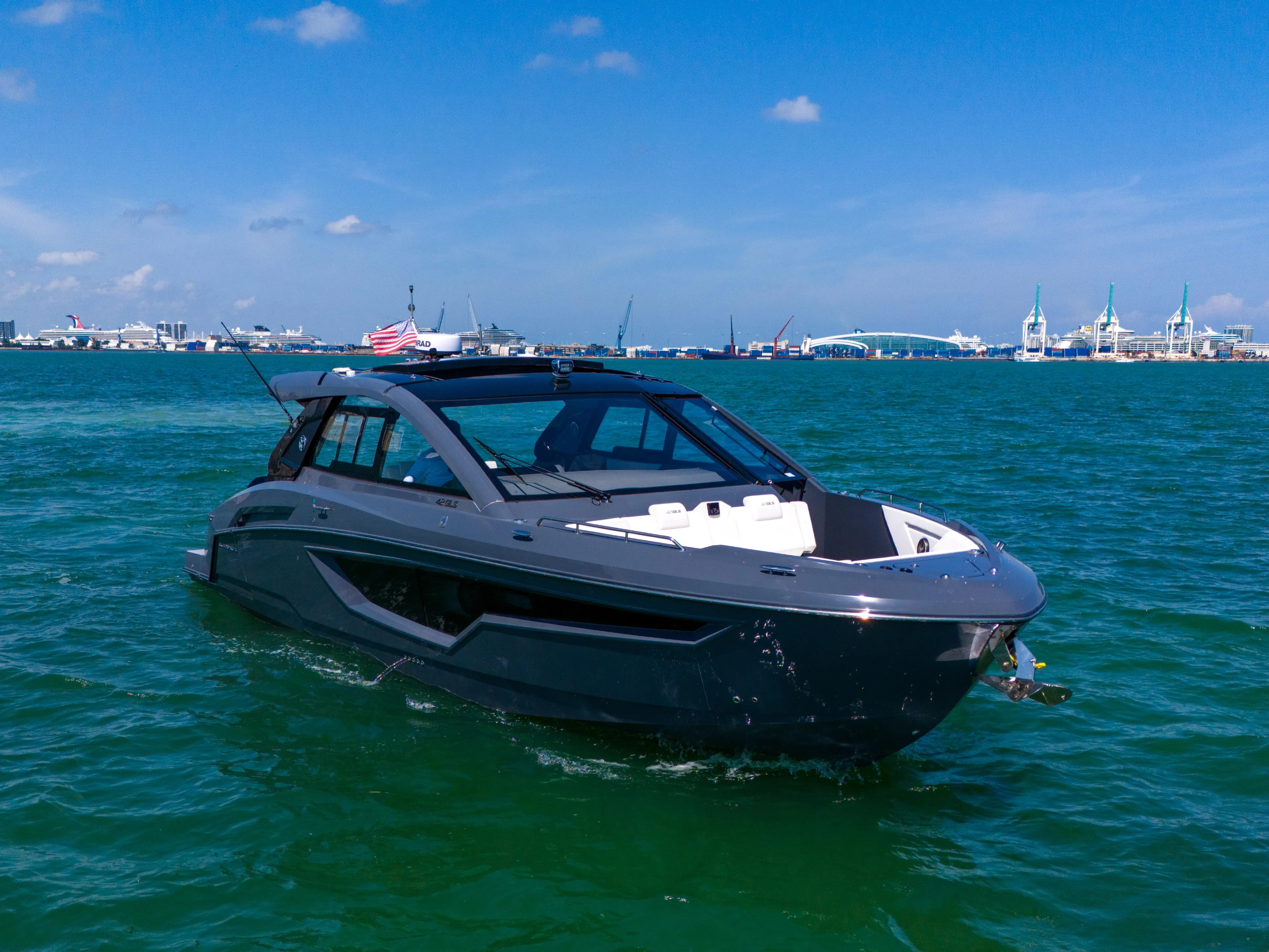  Yacht Photos Pics 2023 Cruisers Yachts 42 GLS OB on blue water, clear sky, distant cityscape.