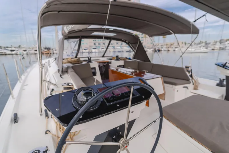 Sacha Marie Yacht Photos Pics 2024 Dufour 470 yacht cockpit with steering wheel, spacious seating, and marina view.