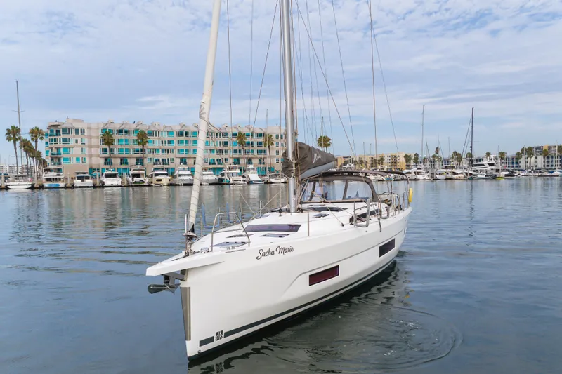 Sacha Marie Yacht Photos Pics 2024 Dufour 470 sailboat in marina, calm waters, modern buildings in background.