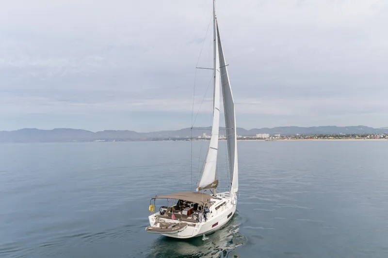 Sacha Marie Yacht Photos Pics 2024 Dufour 470 sailboat cruising on calm waters near a coastal cityscape.